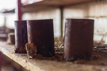 Three old rusty cans are sitting on a wooden shelf
