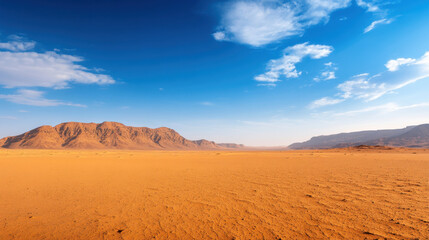 Fototapeta premium panoramic view of vast desert landscape in Saudi Arabia, showcasing golden sands and distant mountains under bright blue sky. scene evokes sense of tranquility and vastness