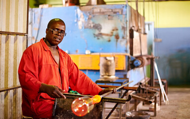 Glassblowing, man and shaping of glass, factory and creative for manufacturing of product and industry. Production, busy and black person in uniform for craft, glassmaker or art for design with tools
