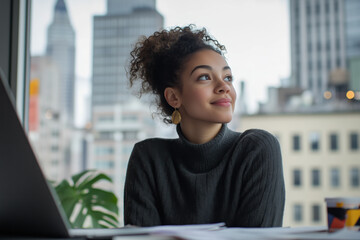 Young woman sitting at her desk smiling and looking thoughtful with an urban cityscape background