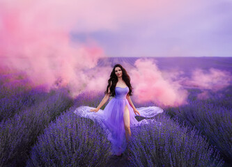 Beautiful woman with long hair in a purple dress in a field of blooming lavender. Fairytale...