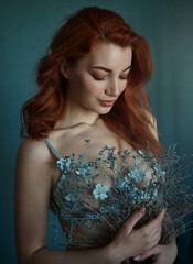 Close up portrait of sensual beautiful red haired woman with blue eyes with flowers.