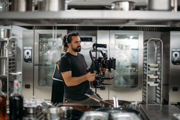 Director of photography with a camera in his hands on the set. Professional videographer at work on filming a movie, commercial or TV series. Filming process indoors, studio