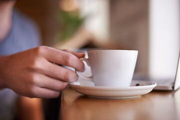 Coffee, hand of person and hospitality in restaurant with laptop, service and relax for remote work. Mug, customer and tea at cafe table for drink, caffeine and cappuccino with tech for networking