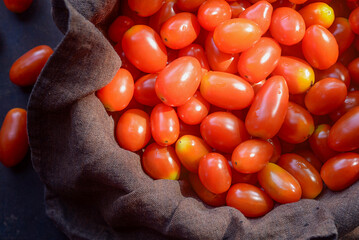red cherry  tomatoes in bowl on brown rustic  background.