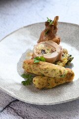 A beautifully presented plate of roasted rabbit pieces with stuffing, including a tender loin roulade and succulent leg, paired with a crispy potato croquette