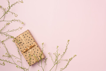 Gift box with flowers on pink background. Flat lay, top view. Copy space