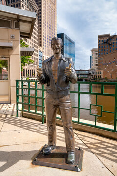 Milwaukee, WI - July 29, 2024: Bronze Fonz landmark in Milwaukee standing along the river with cityscape in background