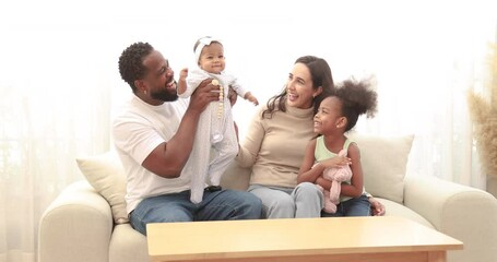 Happy black family laughing playing with children at home cheerful african american parents tickling 2 multiracial kids having fun on couch mom dad with 2 daughter, baby girl enjoying funny activity. - Powered by Adobe