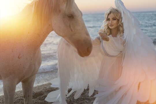 Young long-haired woman in a white dress riding a white horse against a seascape