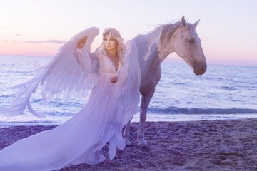 Young long-haired woman in a white dress riding a white horse against a seascape