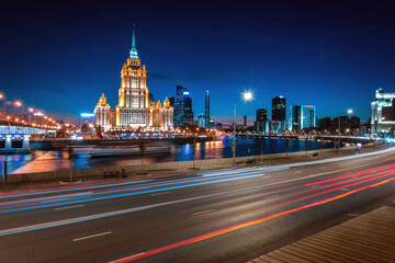 Illuminated high-rise stalinist building near river at summer night in Moscow, Russia. Historic name is Hotel Ukraina. Translation of the inscription on the facade: Ukraine