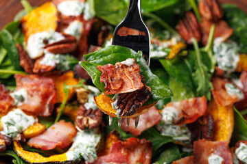 Baked pumpkin bacon salad with spinach and pecan nuts. Healthy food.