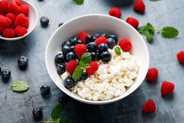 Bowl of cottage cheese, curd cheese with blueberry and raspberry. High protein healthy breakfast or lunch