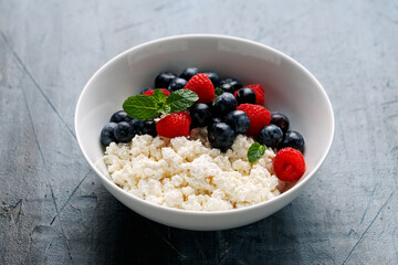 Bowl of cottage cheese, curd cheese with blueberry and raspberry. High protein healthy breakfast or lunch