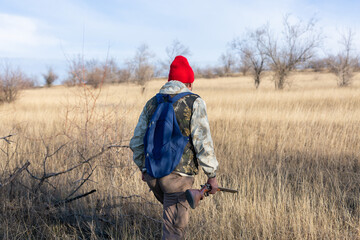 Mature hunter man holding a shotgun and walking through a field