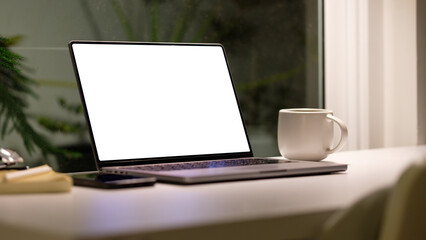 Workspace setup with a laptop and coffee mug, placed near a window offering a subtle view of...