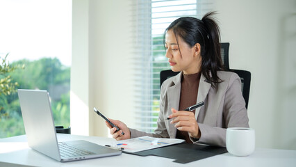 Business executive using mobile phone while reviews documents at desk.