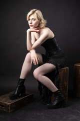 Naklejka premium Expressive young blonde under a bob in the studio. In a black corset and dress.