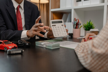 a car salesman is explaining the details of a car and the pricer that a buyer is interested in, the...