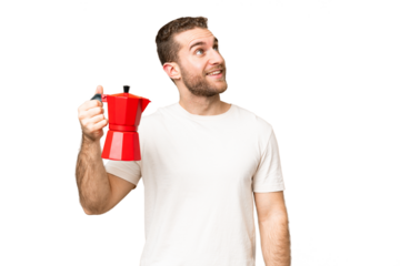 Young handsome blonde man holding coffee pot over isolated chroma key background looking up while smiling