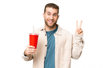 Young handsome blonde man holding soda over isolated chroma key background smiling and showing victory sign
