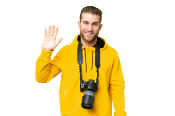 Young photographer man over isolated chroma key background saluting with hand with happy expression
