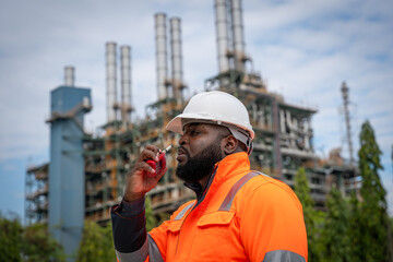 Engineers wearing safety gear, including hard hats examining survey standing industrial facility gas or oil refinery engaged in a job requires high safety standards concept.	