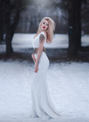 Beautiful blonde in a long white dress in a fairytale winter forest.