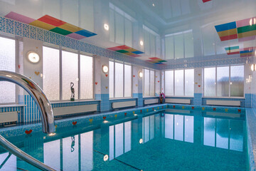 A spacious swimming pool in a private house with panoramic windows. The room is decorated with...