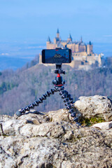 Highlighted against a stunning scenic backdrop, a smartphone on a tripod showcases the grand view...