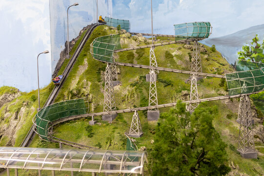 Miniature Mountain Roller Coaster With Winding Tracks And Scenic Greenery On A Hillside