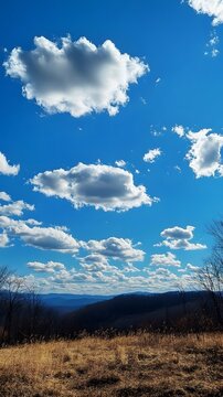 31. A sweeping view of rolling hills under a bright blue sky dotted with fluffy clouds