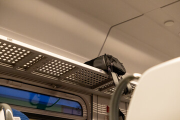 black travel bag placed on overhead luggage rack in train compartment interior during evening journey