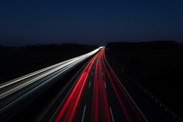 A long-exposure photograph capturing highway traffic at night, creating stunning light trails. The...