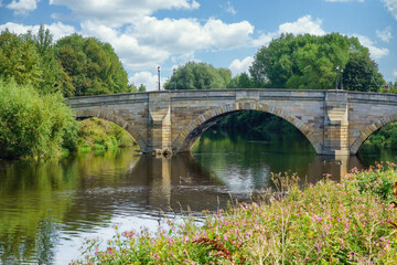 The picturesque Castleford stone bridge spans The River Calder River, its multiple arches reflecting in the calm water, Castleford, West Yorkshire, UK.