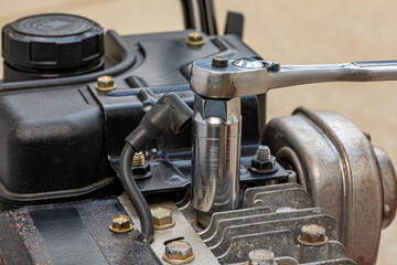 Removing spark plug from lawn mower engine with socket wrench. Lawn and garden equipment repair,...