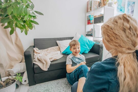professional therapist teaching hand coordination exercises to young boy, therapeutic session at home, concept of sensory integration and child psychology