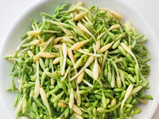 Close-up of uncooked papaya flower vegetables in a white plate on a white background. 
