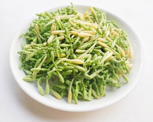 High angle view of uncooked papaya flower vegetables in a white plate on a white background. 