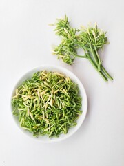 Uncooked papaya flower vegetables in a white plate on a white background. Top of view. 