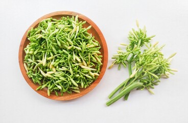Uncooked papaya flower vegetables in a wooden plate on a white background. Top of view. 
