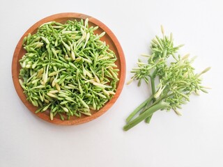 Directly above shot of uncooked papaya flower vegetables in a wooden plate on a white background. Top of view. 