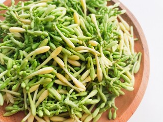 Close-up of uncooked papaya flower vegetables in wooden plate on white background.