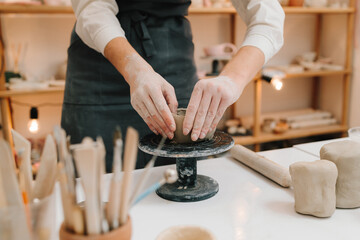 Artisan sculpts ceramic bowl using potter's wheel. Hands shaping clay into dish in the craft studio.