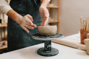 Female potter hands shows ceramic bowl ready for firing in a kiln. The process of creating ceramic...