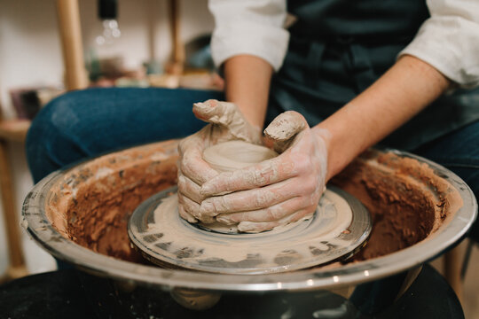 Process of making ceramic earthenware on the spinning wheel in the pottery studio. Artisan molds a piece of wet clay on the pottery wheel.