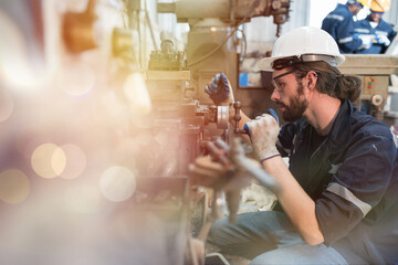 Professional male engineer maintenance lathe machine in industry factory. Engineer repairing lathe machine with safety uniform, goggles and helmet