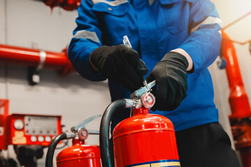 Engineer checks fire extinguisher in fire control room to ensure safety. When an emergency occurs
