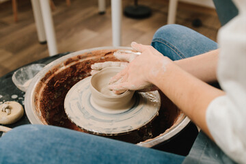 Craftswoman is molding porcelain dish in the pottery studio. Artisan sculpts a pottery plate on the...